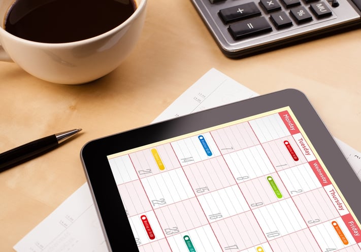 Workplace with tablet pc showing calendar and a cup of coffee on a wooden work table close-up.jpeg