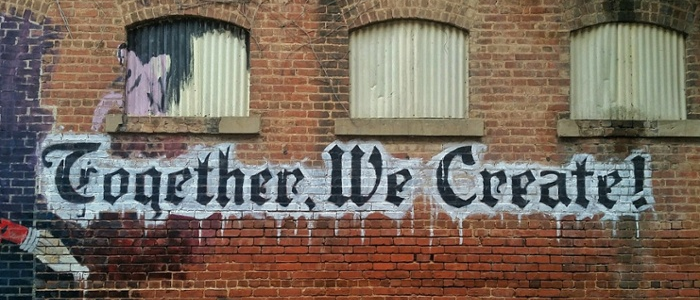 Graffiti on building saying Together We Create