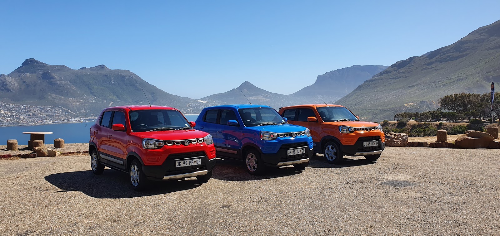 Three Suzuki S-Pressos parked next to each other with mountains in backdrop